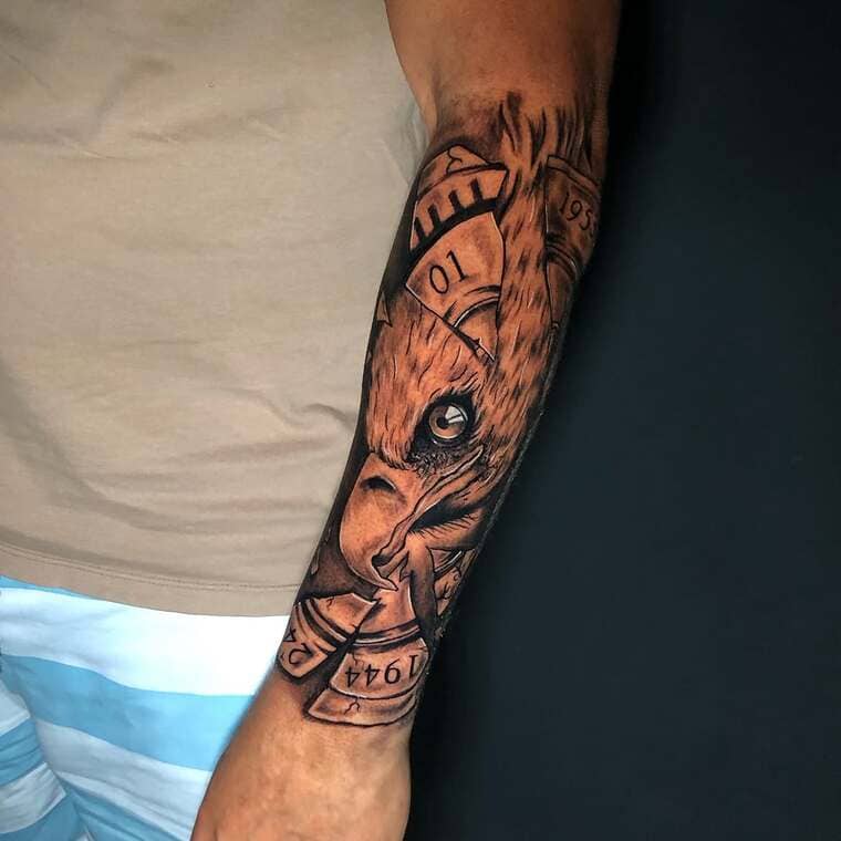 Antebraço fechado no estilo realismo contendo uma cabeça de águia misturado com um relógio.